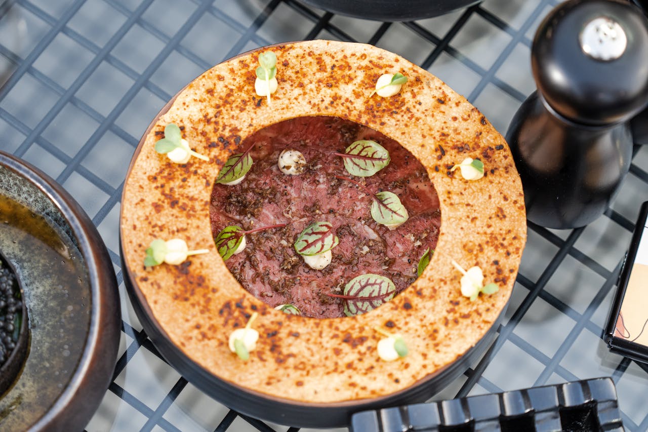 Overhead view of a gourmet meat dish garnished with herbs, encased in a unique artistic bread design.